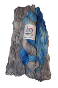 A folded skein of variegated yarn with gray, blue, and white color-shifting yarn blended together, featuring a white paper label in the center.