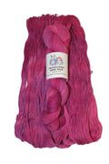 A skein of vibrant magenta and pink ombre yarn with a white paper label, displayed on a neutral light gray background.