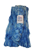 A skein of variegated blue and white yarn with a white paper label, photographed on a plain light background.