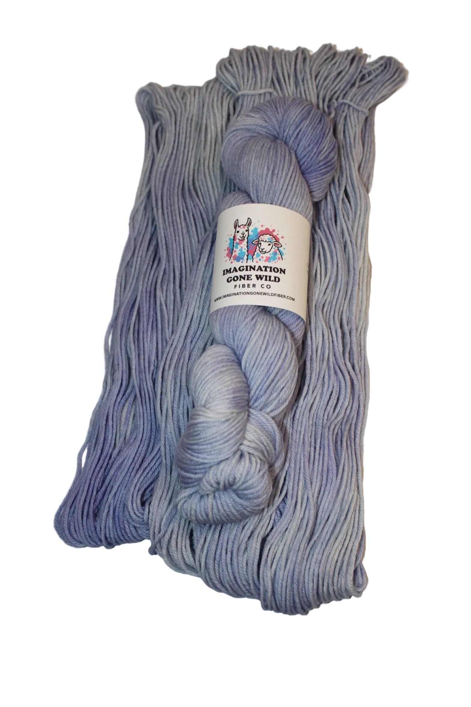 A skein of variegated yarn in a dusty lavender-purple and light blue-gray colorway, wrapped with a white paper label that reads 'Peanut Butter' and 'Purple & Blue'. The yarn is laid flat on a plain white surface.